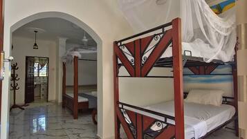 A room with a bed under a canopy, a marble-tiled floor, and a hallway with an arched doorway leading to another room.