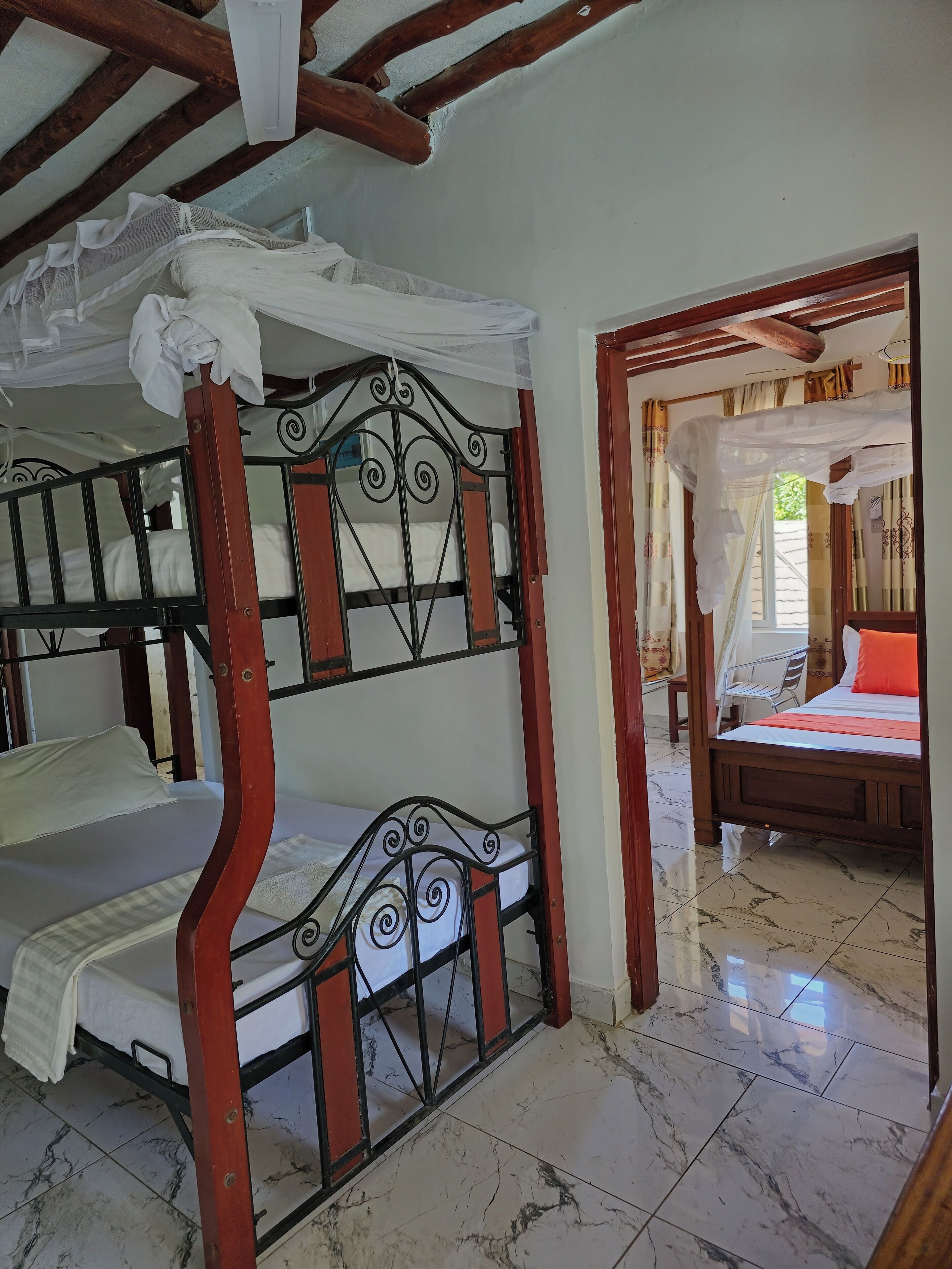 A room with a bunk bed, a separate bed, and a small table.