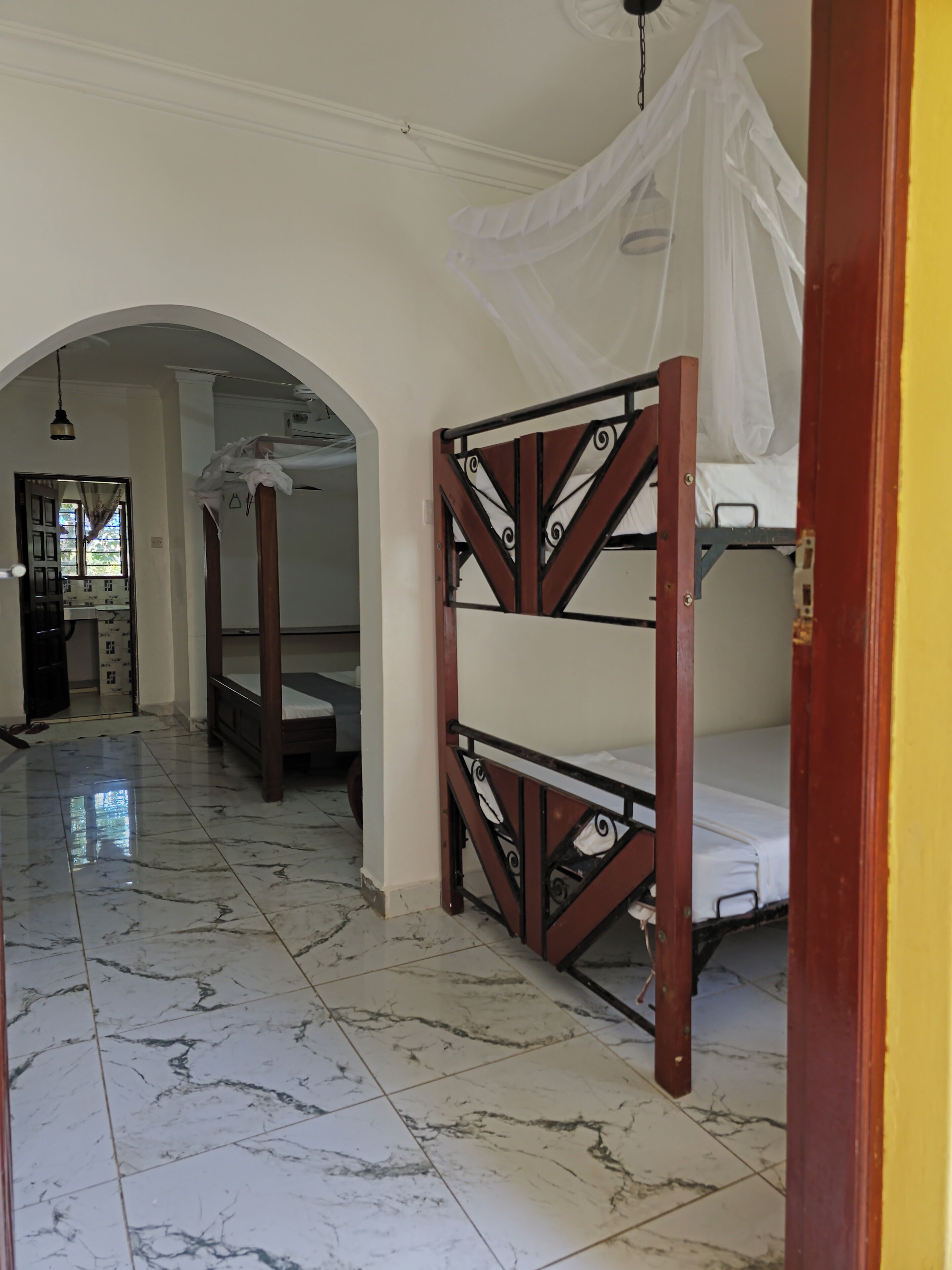 A room with a bed, a ceiling fan, and a tiled floor.
