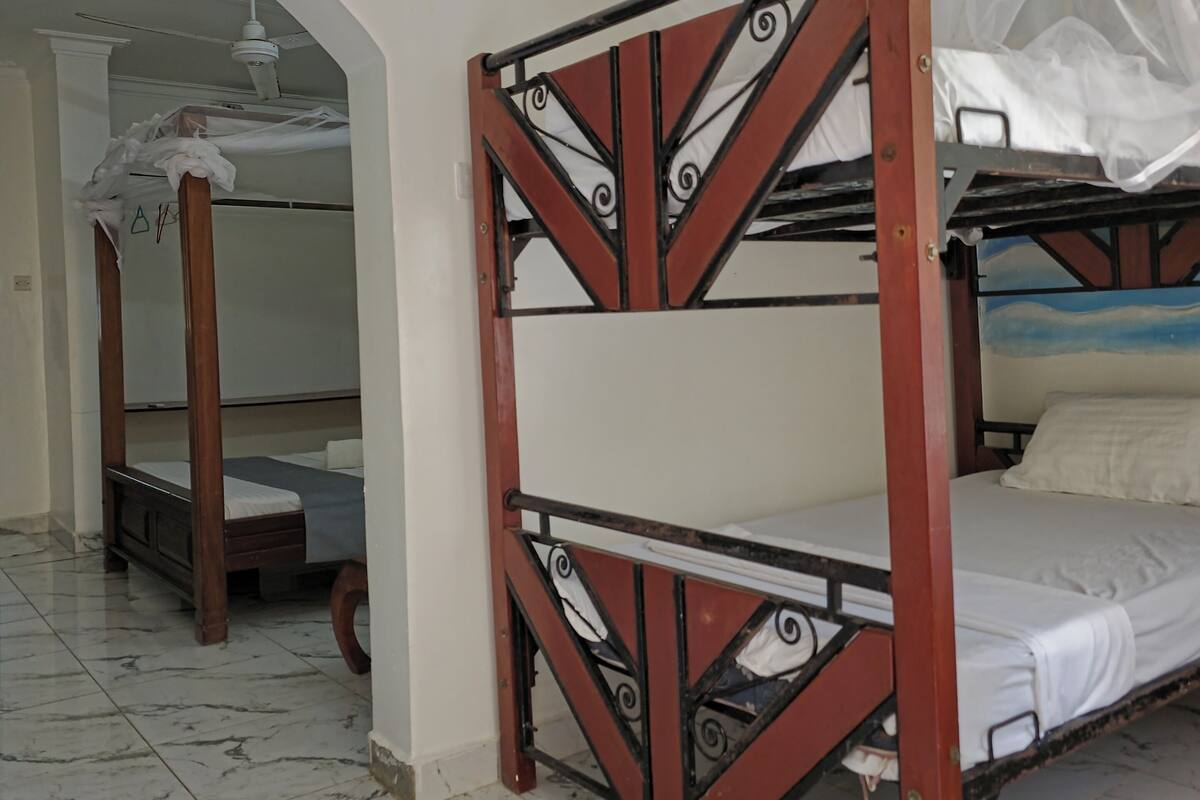 A room with two bunk beds, a ceiling fan, and a tiled floor.