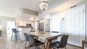 A modern kitchen with a central island, white cabinets, stainless steel appliances, and a chandelier. - The Palms of Destin 21117 by Compass Resorts (Destin)