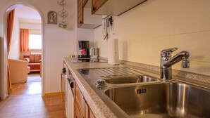 A kitchen with stainless steel sinks, wooden cabinets, and a coffee maker. - Apartment 'Ferienwohnung Doll Waltraud' with Shared Terrace and Balcony (Oberkirch)