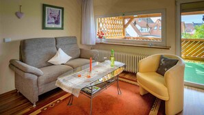 A living room with a sofa, armchair, coffee table, and a view through a window. - Apartment 'Ferienwohnung Doll Waltraud' with Shared Terrace and Balcony (Oberkirch)