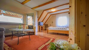 A cozy room with a bed, a small table, a chair, a radiator, and a window with curtains. - Apartment 'Ferienwohnung Doll Waltraud' with Shared Terrace and Balcony (Oberkirch)