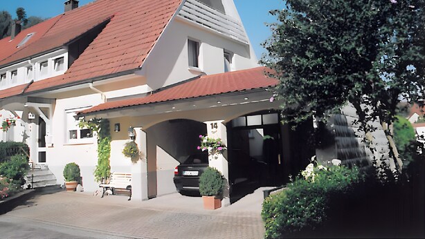 A building with a sloped roof, a garage, and a covered entrance. - Apartment 'Ferienwohnung Doll Waltraud' with Shared Terrace and Balcony (Oberkirch)