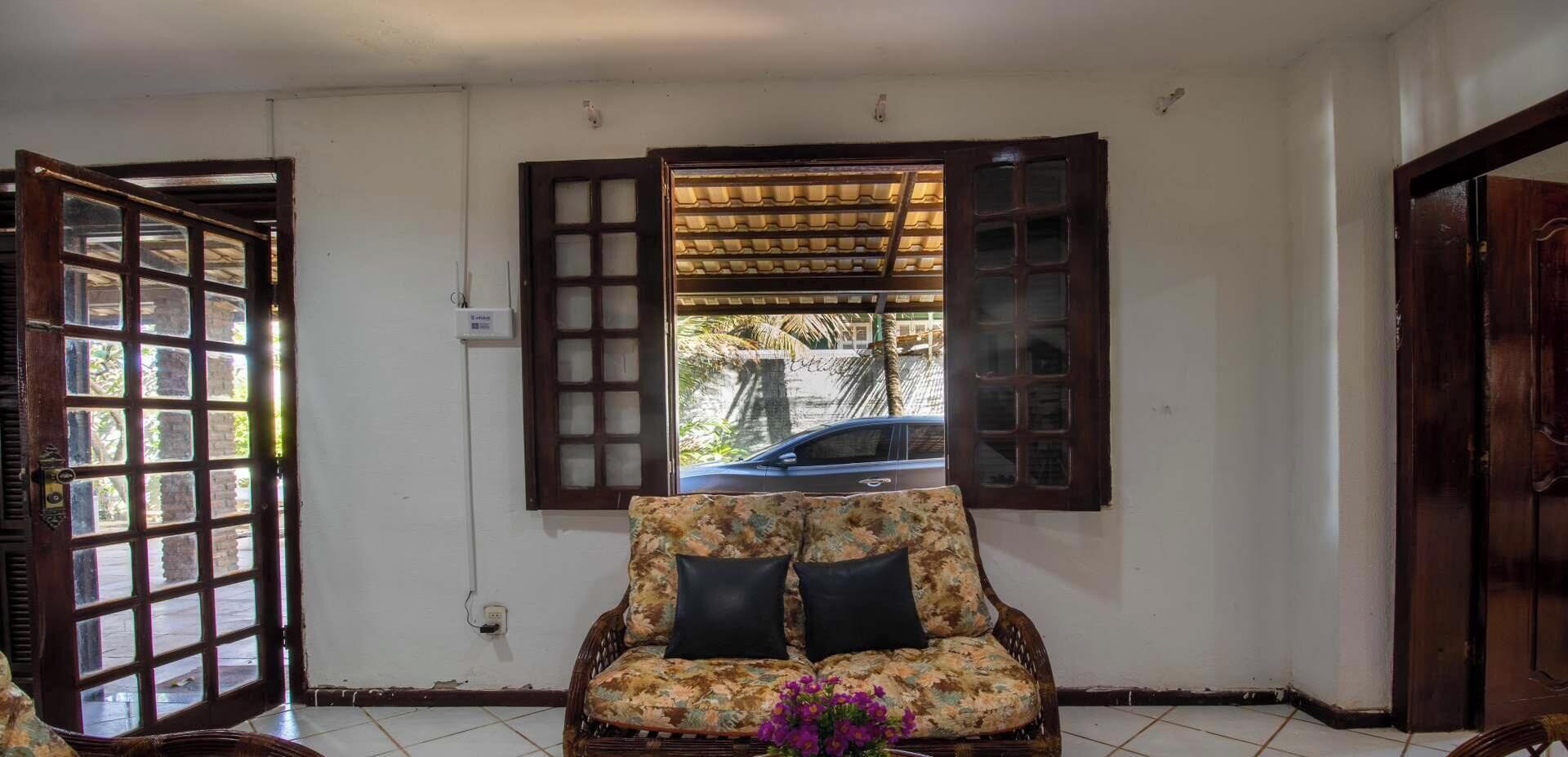 A room with a sofa, a window with open shutters, and a door.
