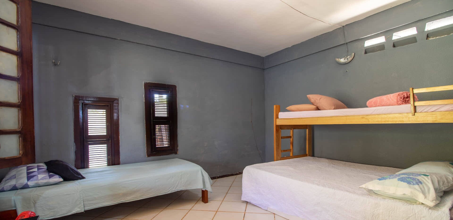 Una habitación con dos camas individuales, una litera y una ventana con persianas.