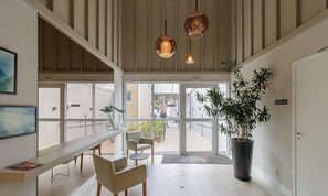 A spacious lobby with a long reception desk, comfortable seating, large windows, and a potted plant. - Studio em Sao Paulo com Lazer Completo (São Paulo)