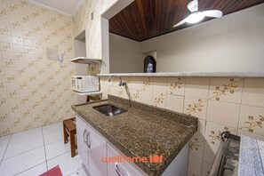 Een koelkast, een magnetron, een kookplaat, kookgerei, borden en bestek