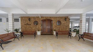 A reception area with a stone wall, wooden benches, and a central door. - Apto em Praia Grande a 500m da Praia do Caiçara (Praia Grande)