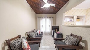 A living room with two sofas, a TV stand, and a ceiling fan. - Apto em Praia Grande a 500m da Praia do Caiçara (Praia Grande)