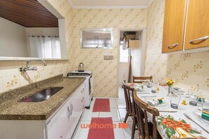 Een koelkast, een magnetron, een kookplaat, kookgerei, borden en bestek