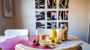 A breakfast table with cereal, fruit, juice, and a cereal jar.