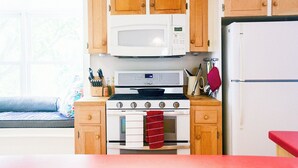 A compact kitchen with wooden cabinets, a white microwave, a stove, and a refrigerator.