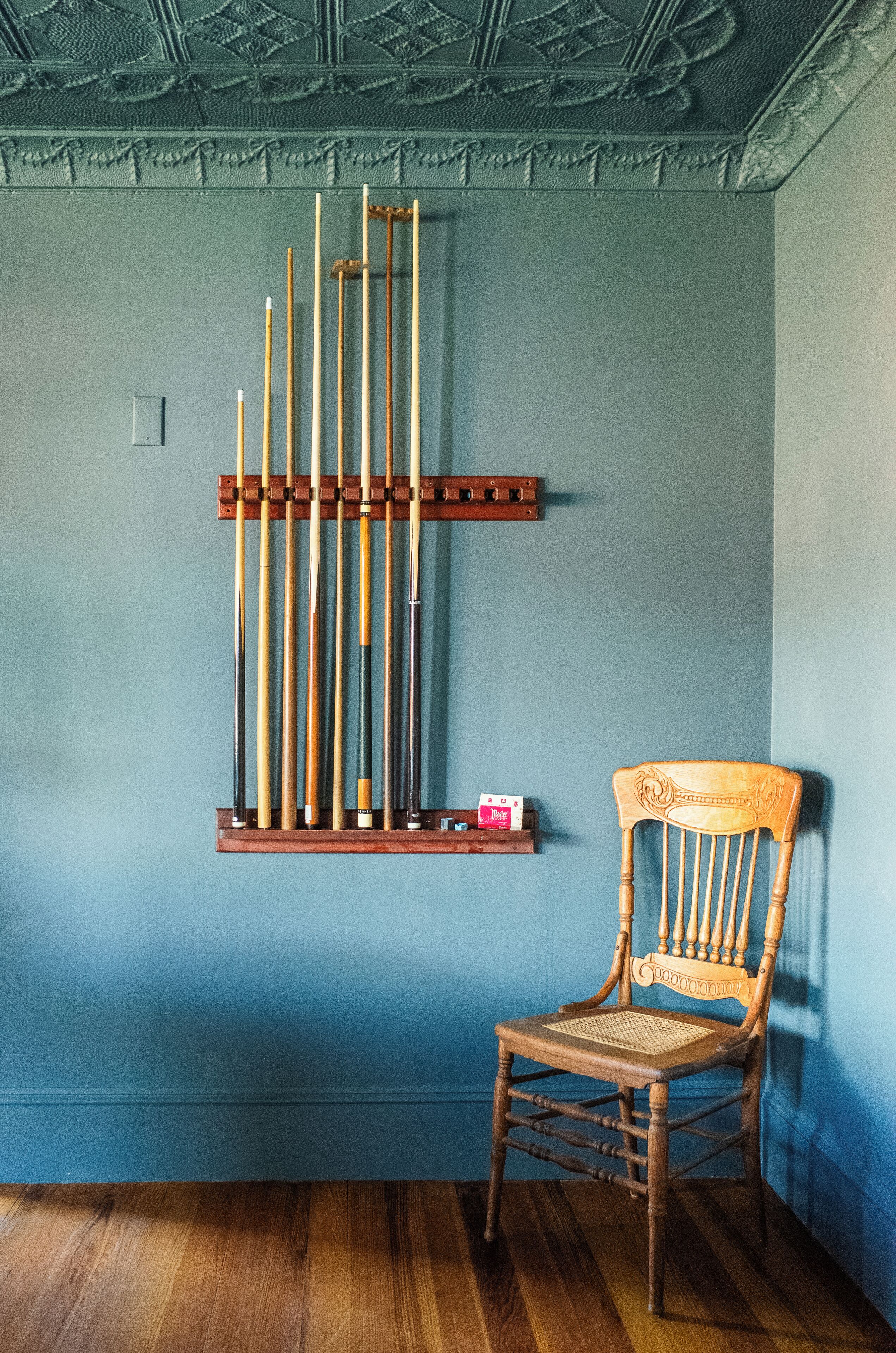 Una stanza con una sedia di legno e un portacque a muro blu.