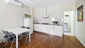Une cuisine compacte avec des meubles blancs, un four à micro-ondes et un évier. On y trouve également une table à manger avec des chaises.