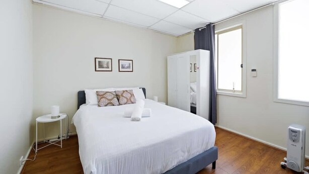 Une chambre d’hôtel avec un grand lit, une armoire, une petite table de chevet et un radiateur.