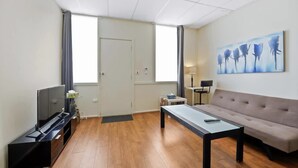 Un salon moderne avec un téléviseur à écran plat, un canapé, une table basse et un tableau accroché au mur.