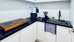 Eine moderne Küche mit weißen Schränken, einer schwarzen Arbeitsplatte, einem Herd, einer Mikrowelle und einem Spülbecken.