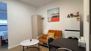 Ein kompakter Wohnbereich mit einer Couch, einem kleinen runden Tisch und einer Küchenzeile.