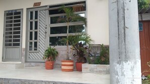 Ein Gebäude mit einem großen Fenster, einer Tür mit einer Nummer und mehreren Blumentöpfen auf der Veranda.