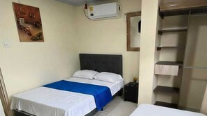 Ein Schlafzimmer mit einem Bett, einem Nachttisch, einem Kleiderschrank und einer Klimaanlage.