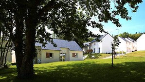 A row of white houses with sloped roofs, surrounded by green grass and trees. - House in Audierne With Heated Pools (Audierne)