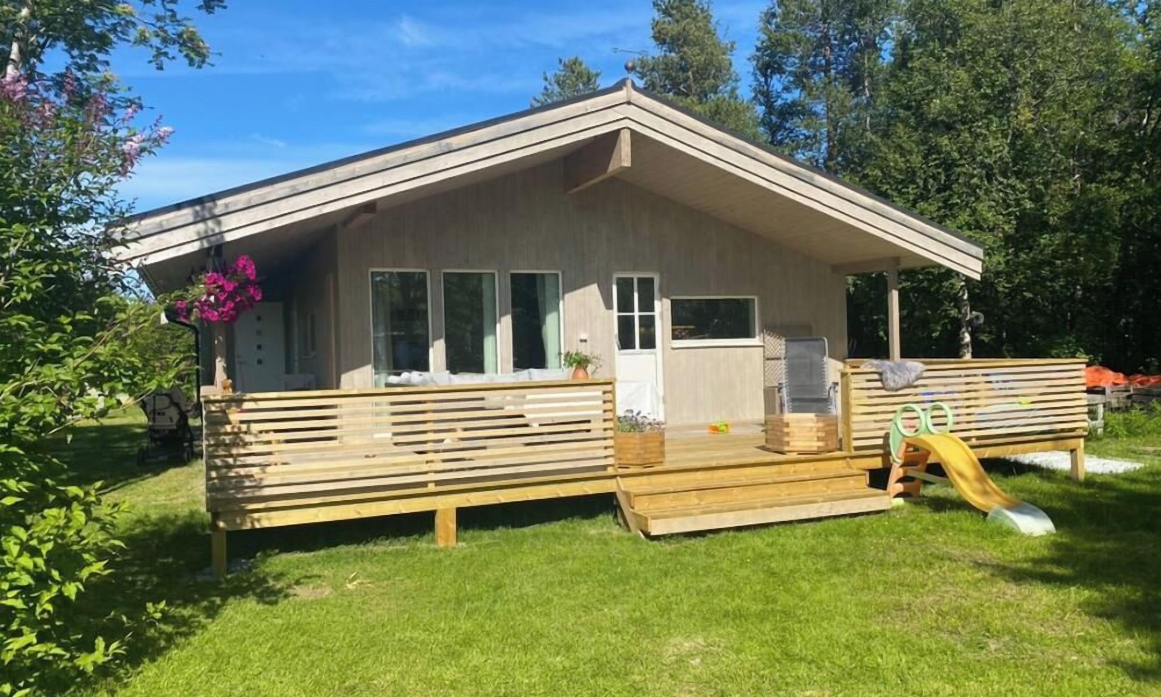 A single-story building with a covered porch, a wooden deck, and a slide.