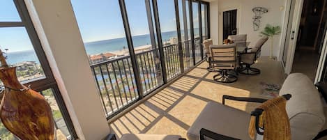 Un balcón con vistas al mar, un ventilador de techo y un comedor con sillas y una mesa.