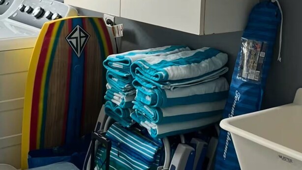 Une salle de bain avec un lavabo blanc, un rideau de douche bleu et une pile de serviettes pliées.
