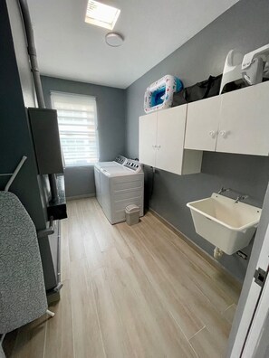 Ein kleines Badezimmer mit Waschmaschine, Waschbecken und Schrank.