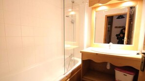Une salle de bain avec une douche à parois de verre, un lavabo et un miroir.