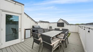 Eine Außenpatio mit Tisch und Stühlen, einem Grill und einer Schiebetür.