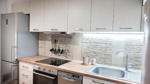 A modern kitchen with light-colored cabinets, a built-in stove, a dishwasher, and a large sink. - PSV Mitropoleos  (Thessaloniki)