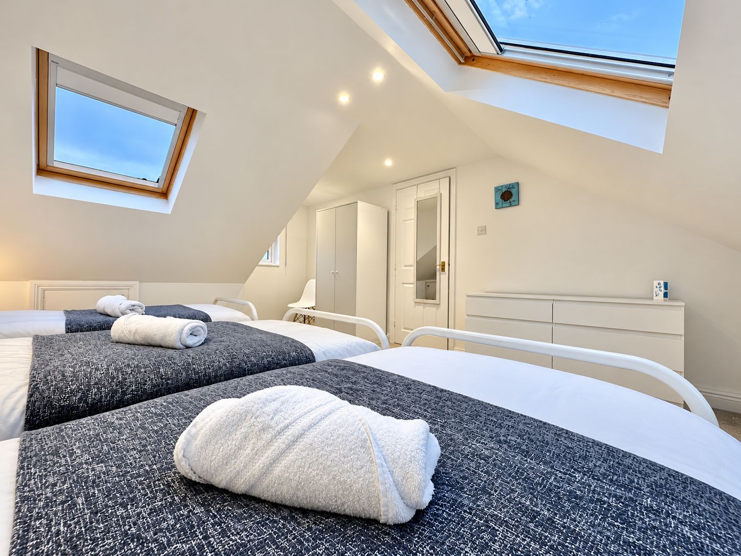 Une chambre d’hôtel avec deux lits, une lucarne, une armoire et un miroir.