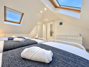 A hotel room with two beds, a skylight, a wardrobe, and a mirror. - Spacious Seaside Home in Peaceful Coastal Setting - 5 Minutes Walk to the Beach (Bournemouth)