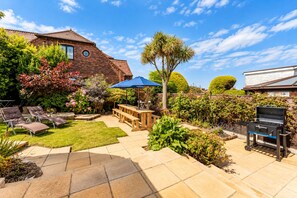 A backyard with a barbecue grill, outdoor seating, and a well-maintained garden.