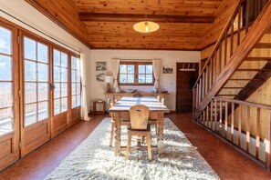 Ein Holzinnenraum mit Esstisch, Stühlen, Teppich und Treppe.