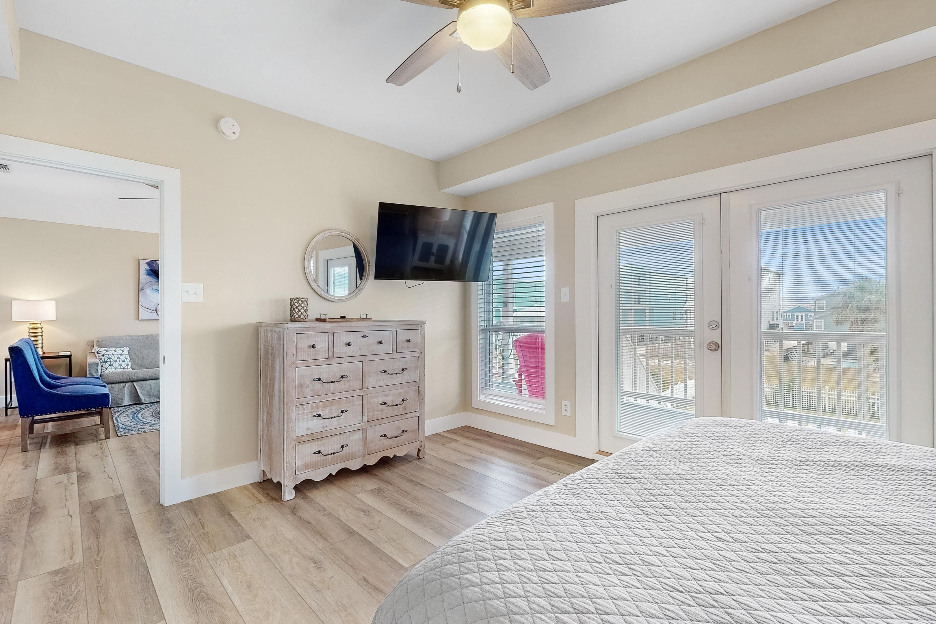 Une chambre à coucher avec un lit, une commode, un téléviseur et un ventilateur de plafond.