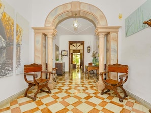 A hallway with a checkered floor, two wooden chairs, a clock, and a door leading to another room. - Casa Can Virolla Gran ·Your house with private pool in Sa Pobla. (Sa Pobla)