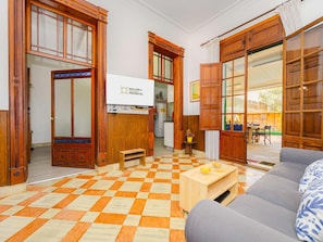 A spacious living area with a checkered floor, wooden furniture, and a view to the outside. - Casa Can Virolla Gran ·Your house with private pool in Sa Pobla. (Sa Pobla)
