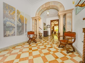 A hallway with a checkered floor, wooden chairs, and paintings on the walls. - Casa Can Virolla Gran ·Your house with private pool in Sa Pobla. (Sa Pobla)