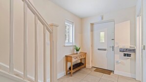 A hallway with a wooden console table, a door, and a window with blinds. - 3 Bedroom Cosy-home in Hornchurch With hot tub (Hornchurch)