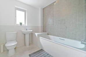 Ein modernes Badezimmer mit Toilette, Waschbecken und Badewanne.
