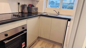 Een kleine keuken met een inbouwoven, een broodrooster en een spoelbak.