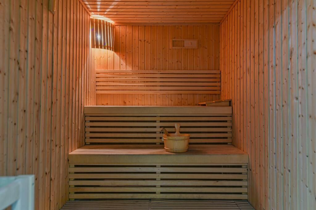 A sauna with wooden benches and a wooden bucket.
