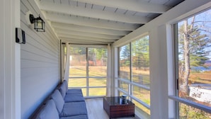 A sunlit room with a long bench, a small table, and large windows offering a view of the outdoors. - Lake-View Spofford Apartment w/ Shared Dock! (Spofford)