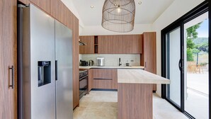 A modern kitchen with wooden cabinets, stainless steel appliances, and a large island. - Douceur de vivre tropezienne: renovated house near beach and village (Gassin)