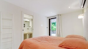 A bedroom with a bed, a wardrobe, and a bathroom visible through an open door. - Douceur de vivre tropezienne: renovated house near beach and village (Gassin)