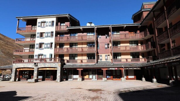 Een hotel met meerdere verdiepingen, balkons, een koffiebar en een bord met daarop een ski-oord.